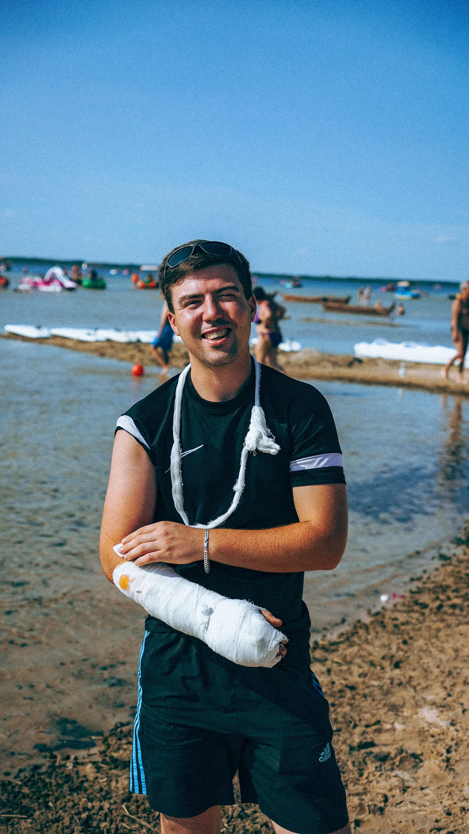 Smiling man wearing an arm cast at the beach