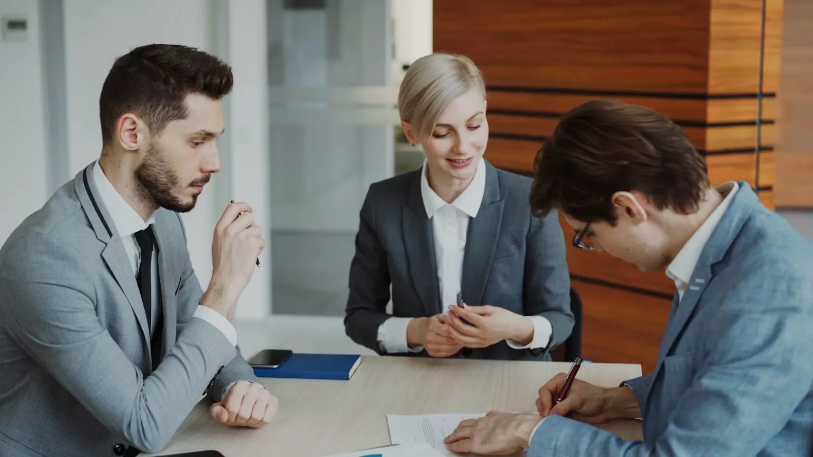 Business people signing a contract across a conference table