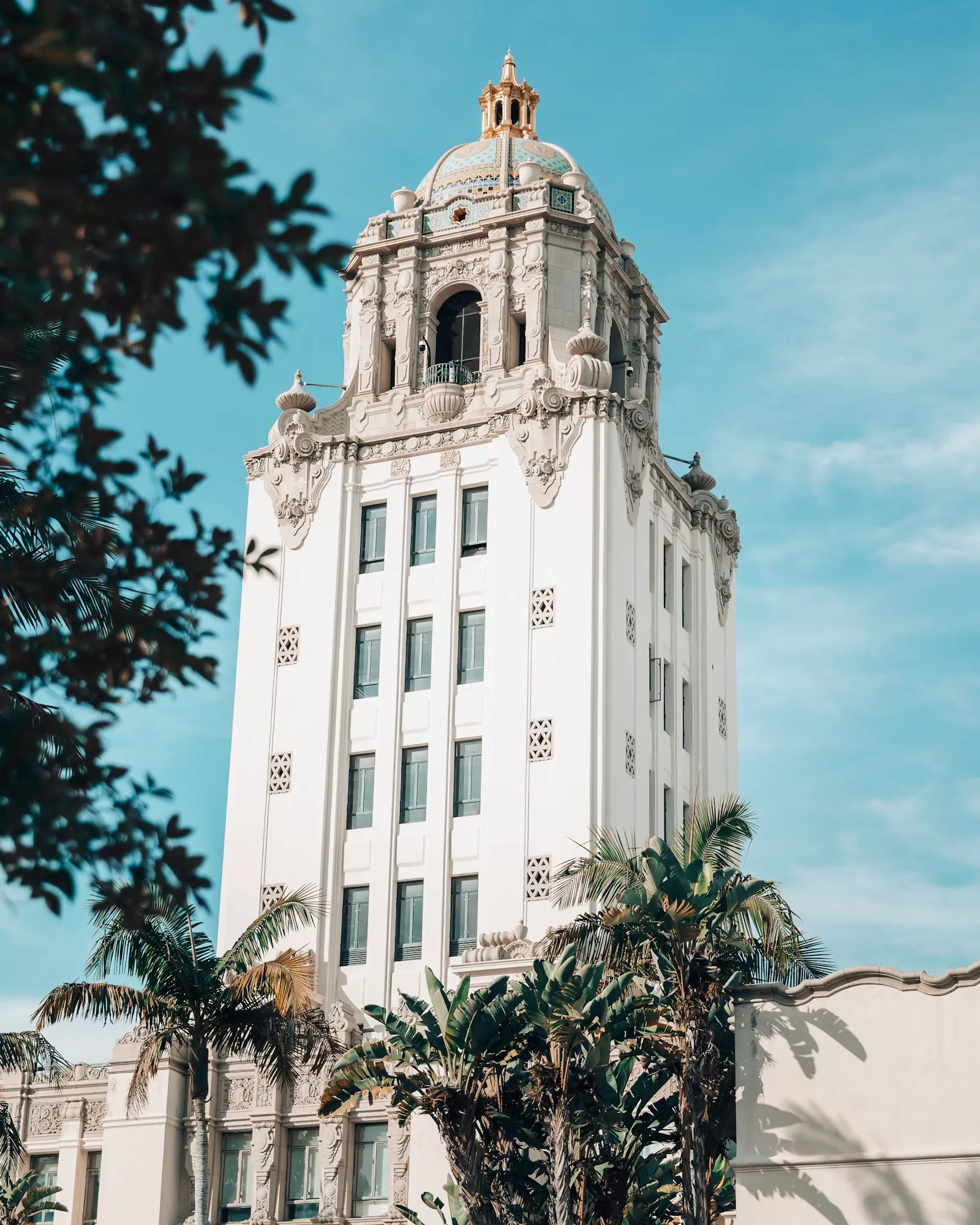 Ornate white civic building framed by palm trees under a blue sky