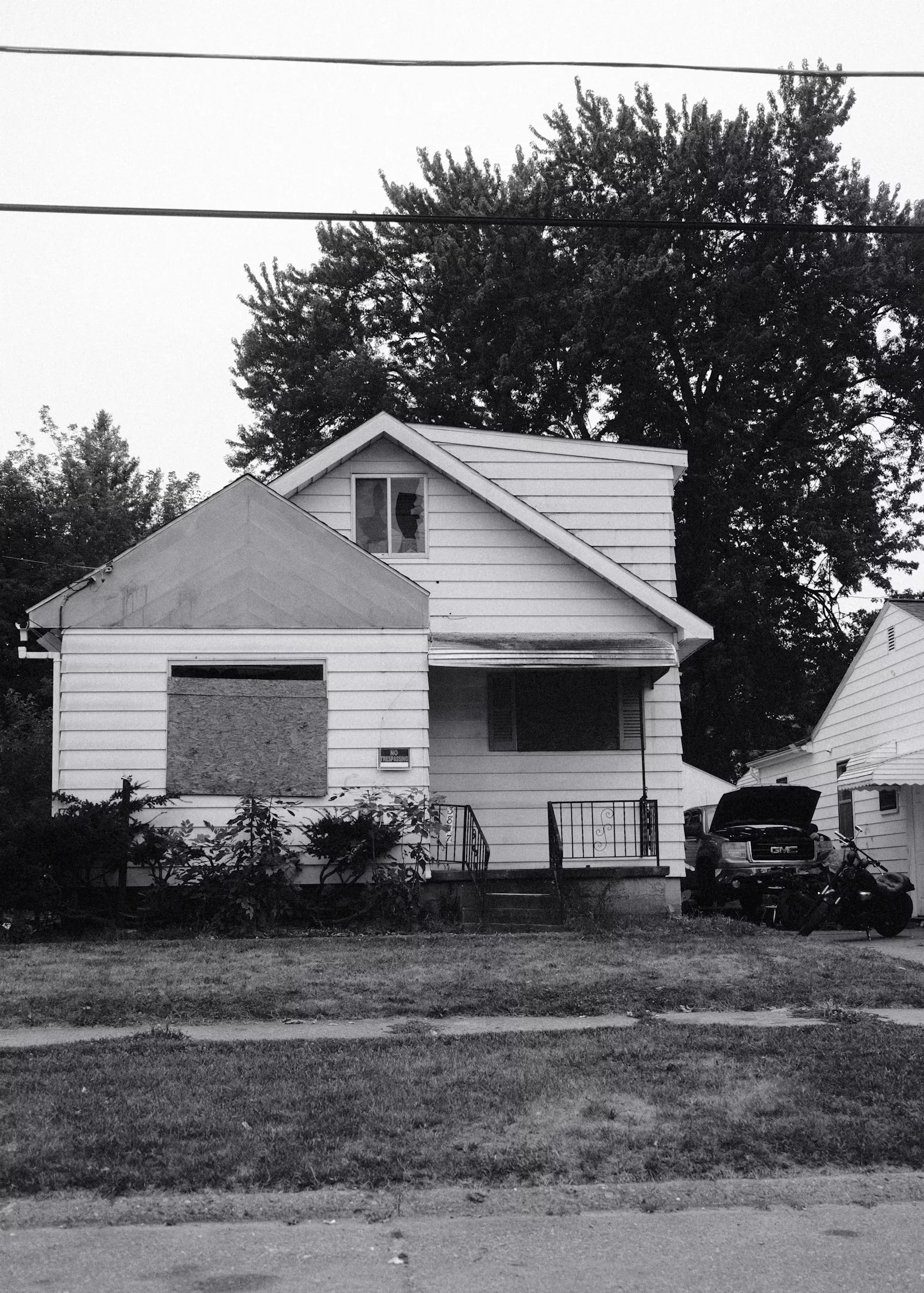 White single-family house with boarded windows and a truck in the driveway