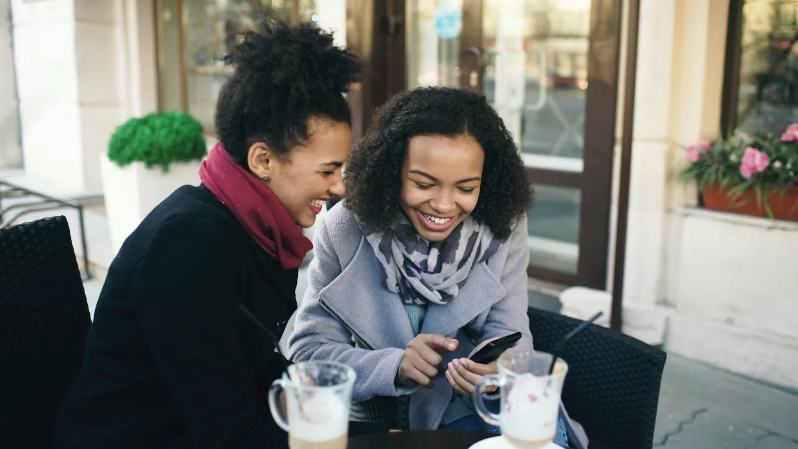 Two women laughing while looking at a phone together