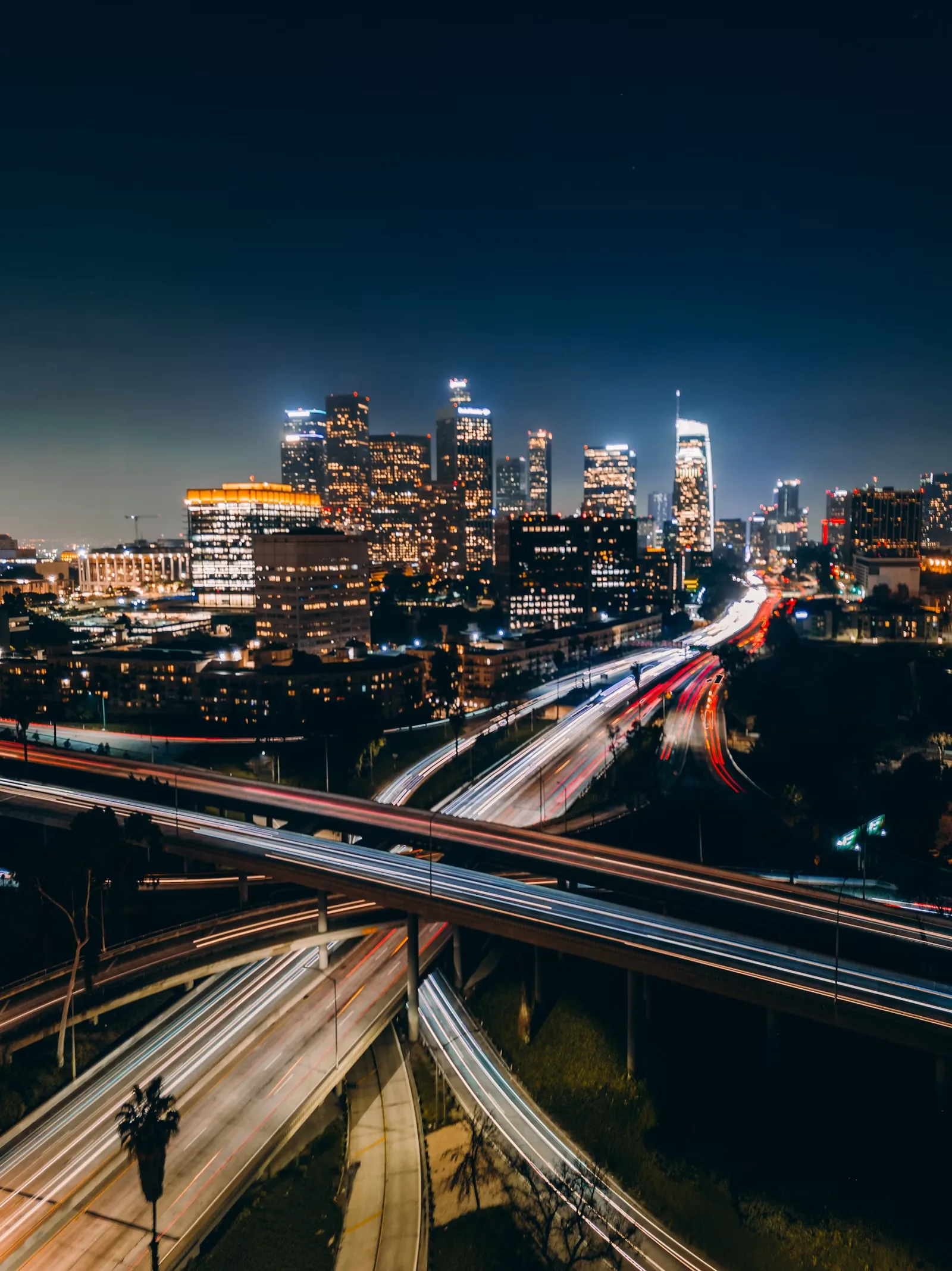 Long-exposure light trails of freeway traffic passing under a bridge at night
