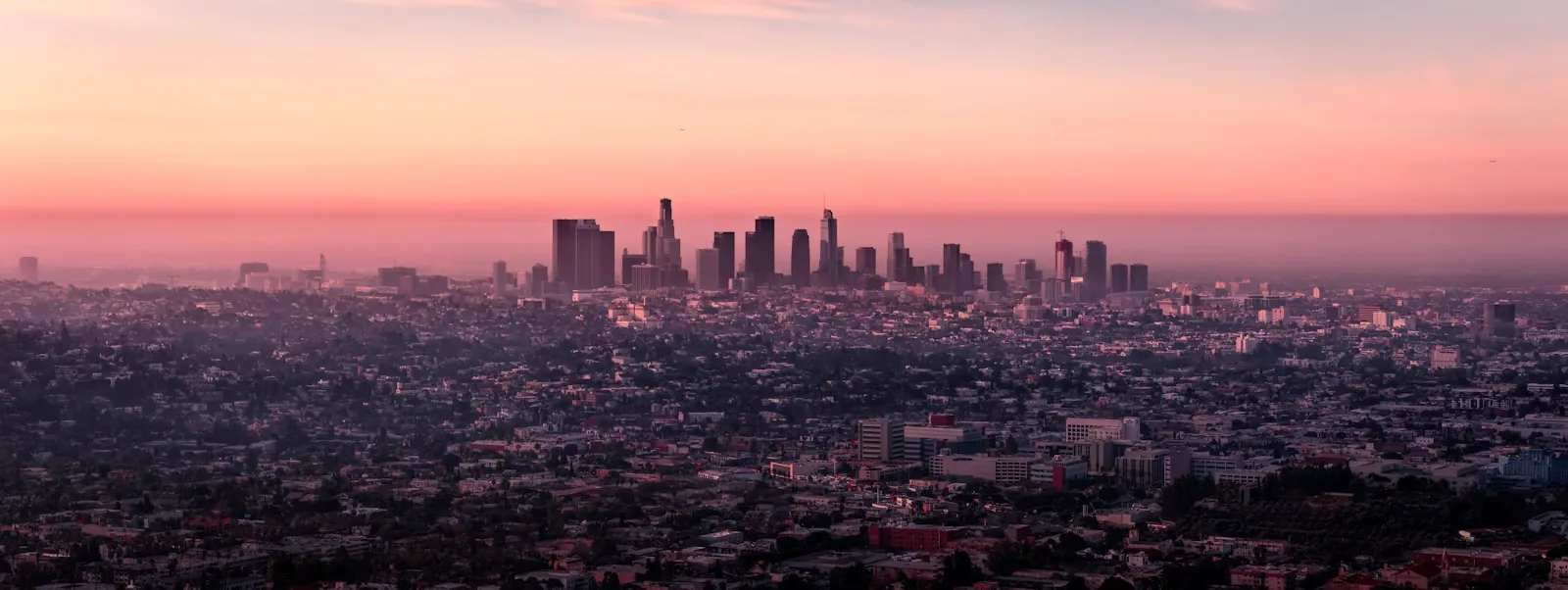 Downtown Los Angeles skyline under a soft pink dusk sky