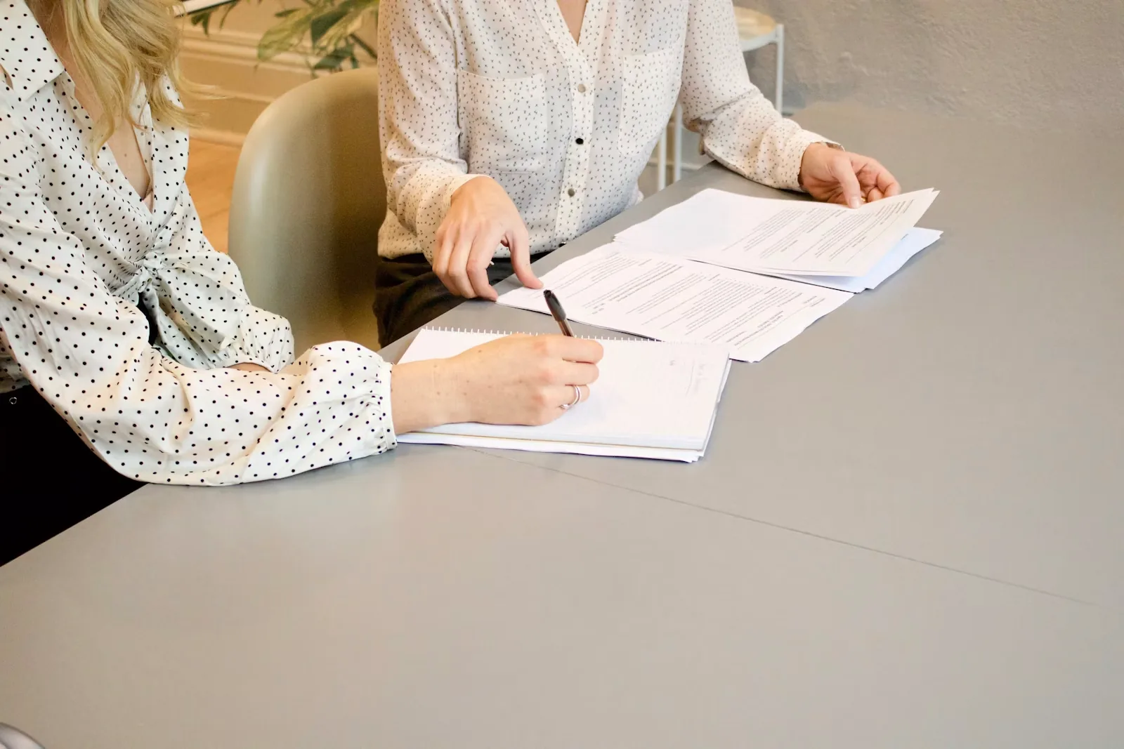 Woman signing a legal document while an advisor points to the page