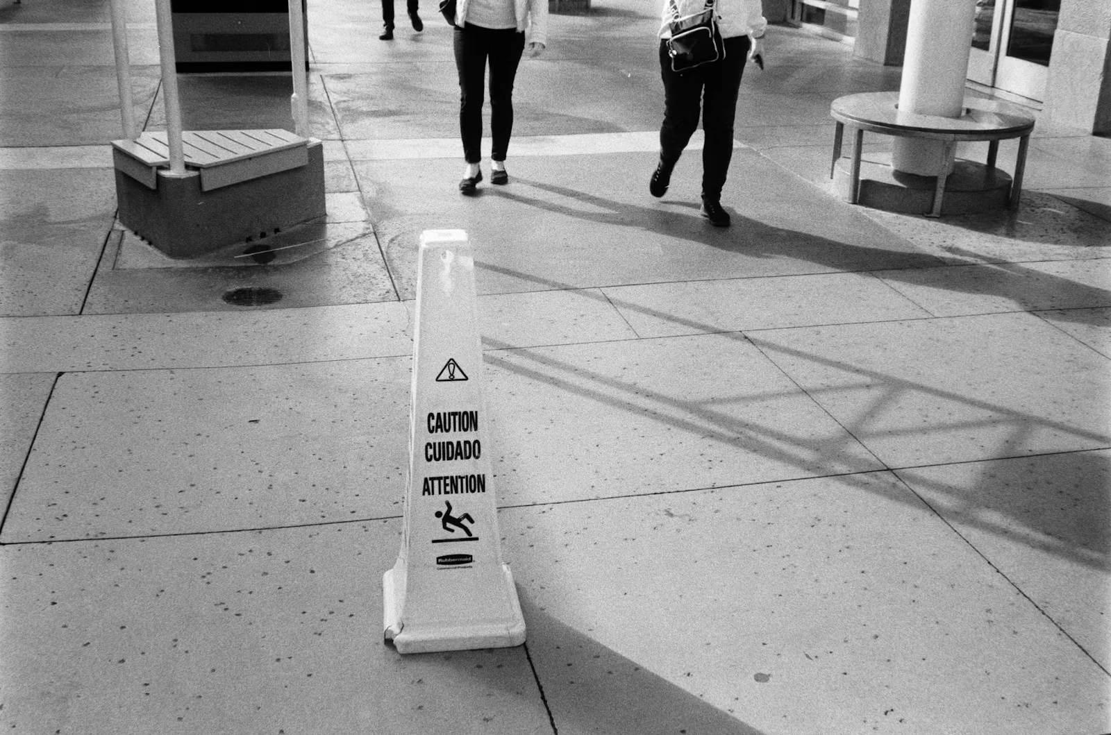 Yellow wet-floor caution sign on a busy sidewalk with people walking past